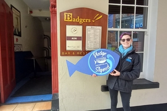 Gala Podgornik holding the Sustainable Fish Cities Pledge in front of the Badgers Bar and Restaurant