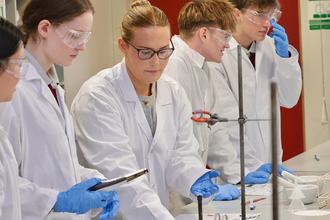 Josephine with school pupils dressed in white lab coats are conducting experiments