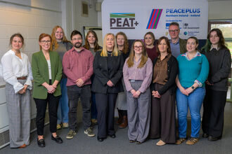 Members of the PEAT+ team standing together for a group photo in front of project branding
