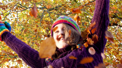 Girl throwing autumn leaves in the air
