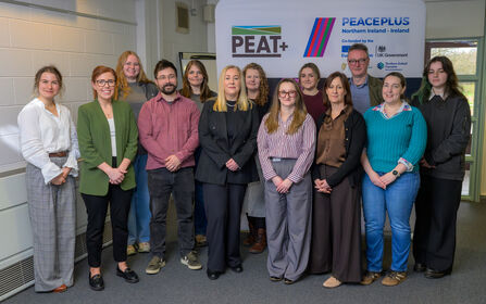 Members of the PEAT+ team standing together for a group photo in front of project branding